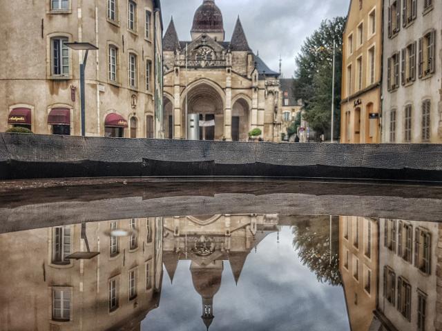 Collegiate church on a rainy day mirror water fountain Beaune