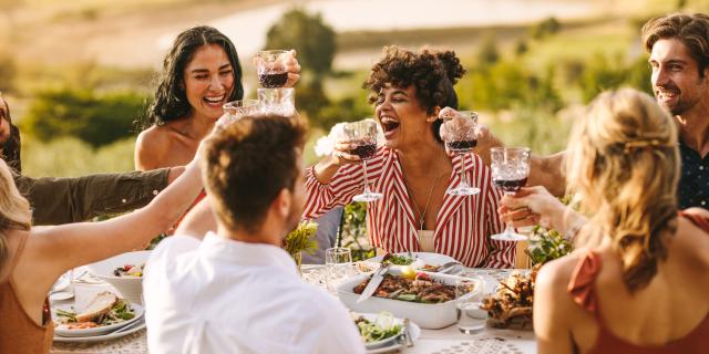 Group of cheerful friends having wine at dinner party. Multi-ethnic people having a get together outdoors.